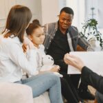 Photo of a Girl Looking at a Card with Her Parents