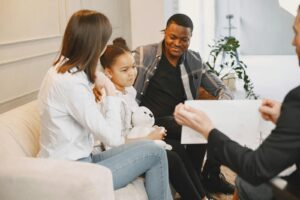 Photo of a Girl Looking at a Card with Her Parents