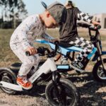 A young boy riding a small blue and white bike