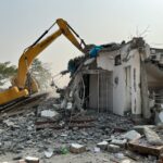 a bulldozer digging through a demolished building